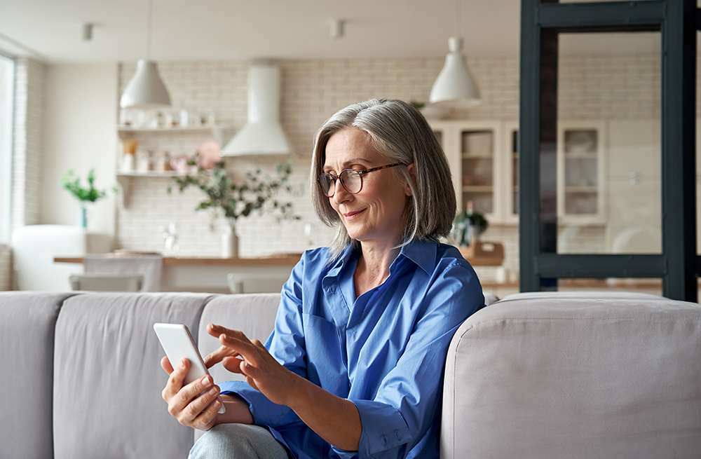 Woman using a cell phone to learn about Eversense E3 System CGM cost.